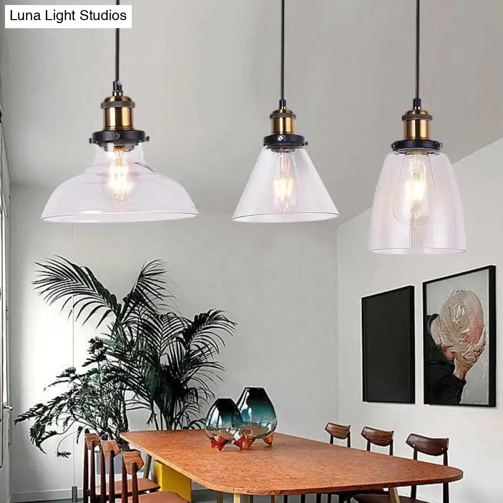 Three industrial style brass pendant lights with clear glass shades hang above a wooden dining table in round barn admix design