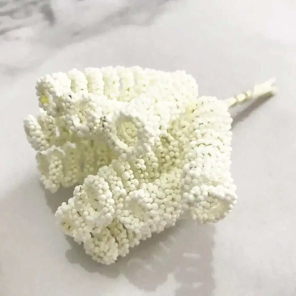 A delicate decorbites ivory flower cherry cluster with white beaded stamen and textured ruffled design on thin stem