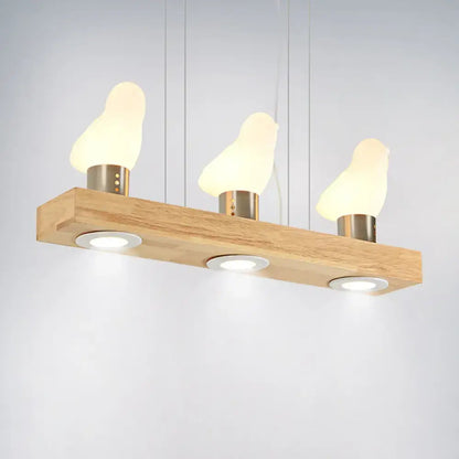 Decorbites ivory glass bird island pendant lighting fixture with three warm glowing bird island pendant lamps on wood plank