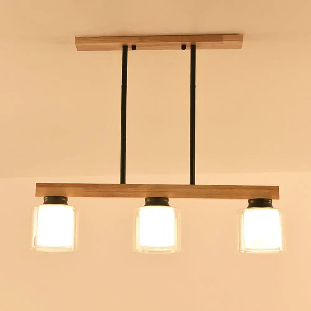 Modern wooden pendant light with three frosted white glass cylinder shades and black metal accents for dining room island