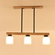 Modern wooden pendant light with three frosted white glass cylinder shades and black metal accents for dining room island