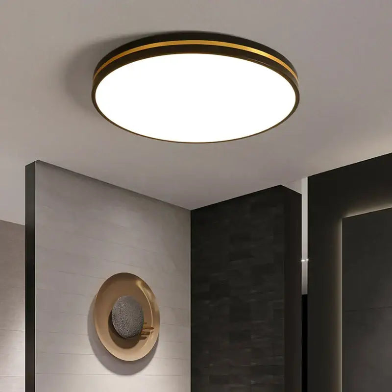 Modern circular DecorBites LED ceiling light with black metal frame and gold rim emitting bright white illumination