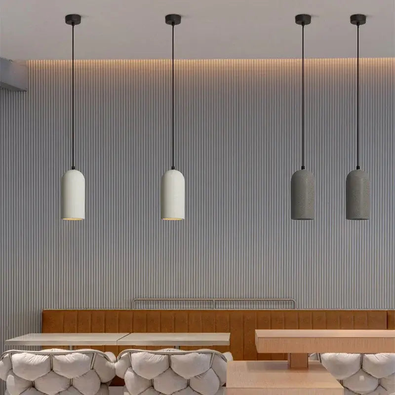Four white and gray ceramic shades hang from black cords in the DecorBites led cement chandelier for bedroom use