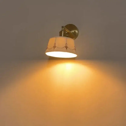 Warm-toned brass finish decorbites led ceramic wall lamp with cream fabric shade and red embroidery pull chain switch