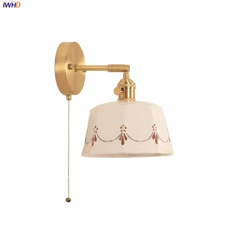 Cream-colored decorbites led ceramic wall lamp with red black motifs and brass finish mounted on a wall sconce