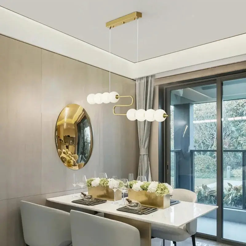 Gold-toned DecorBites LED chandelier with curved metal frame and white glass bulbs for dining room lighting