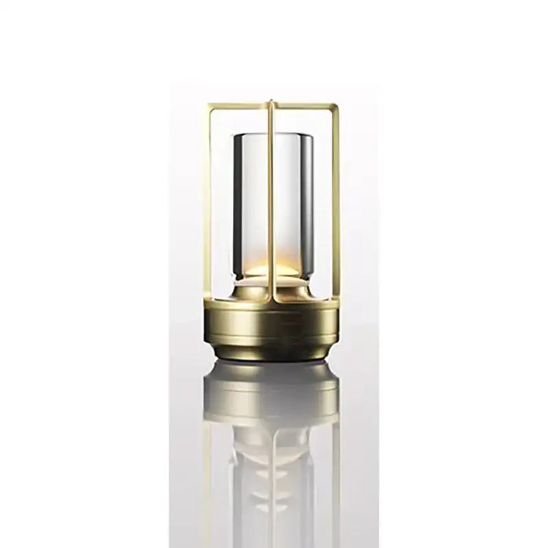 Gold-toned decorbites™ led crystal table lamp with clear glass cylinder and brass frame emitting warm light
