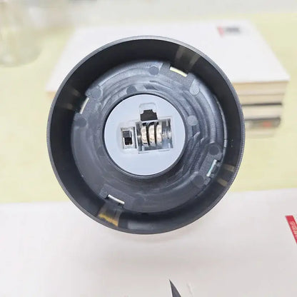 Black plastic flashlight head with internal battery compartment and metal spring mechanism for DecorBites™ eternal rose light
