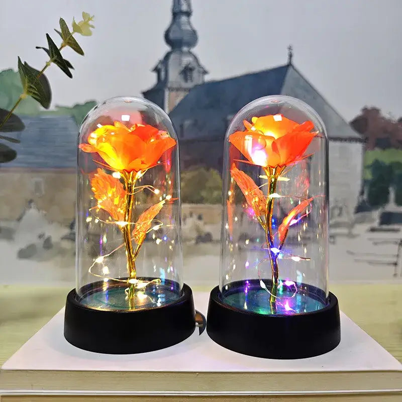 Two golden-leafed roses with glowing orange petals in glass domes on black bases decorbites™ eternal rose light for weddings