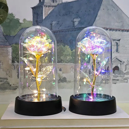Two illuminated glass dome eternal rose lights glowing warm yellow gold and cool purple blue for weddings and valentines
