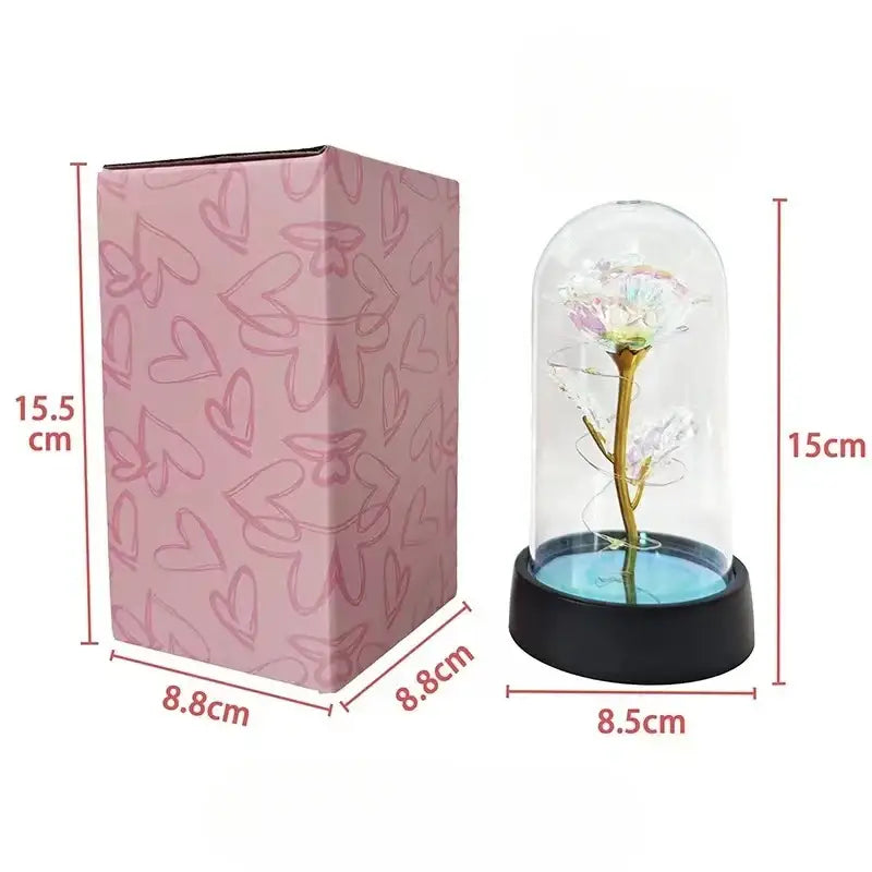 A delicate iridescent eternal rose light with golden stem displayed inside a clear glass dome on a black base
