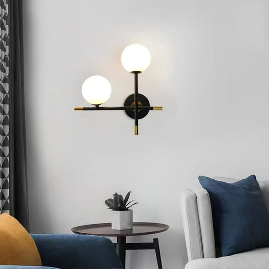 Modern black and brass DecorBites LED glass ball wall lamp with two glowing spherical shades for bedroom lighting