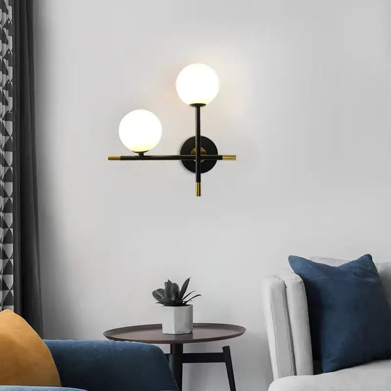 Modern black and brass DecorBites LED glass ball wall lamp with two glowing spherical shades for bedroom lighting