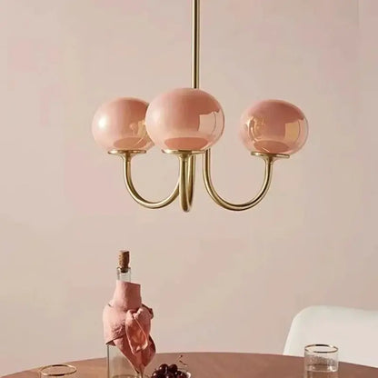 A delicate three-light decorbites led glass chandelier with rose-tinted glass balls and polished brass frame for home decor