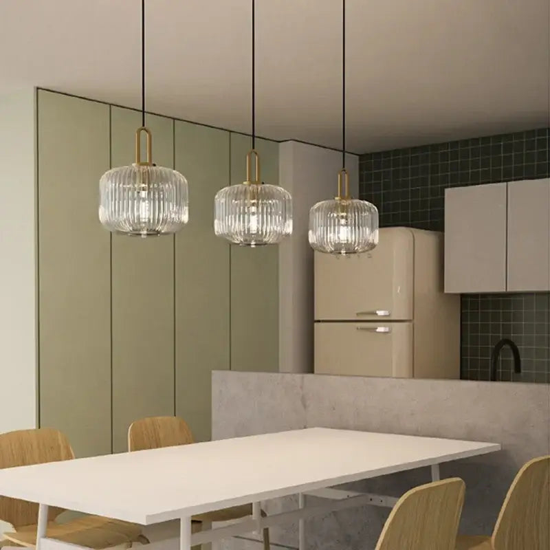 Three elegant glass pendant lights with brass accents hang above a modern dining table in decorbites led glass chandelier