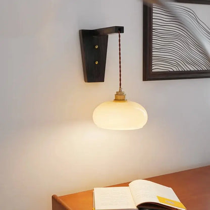 Warm-toned oval led glass sconce wall lamp with brass fixture and dark wood bracket by decorbites led glass
