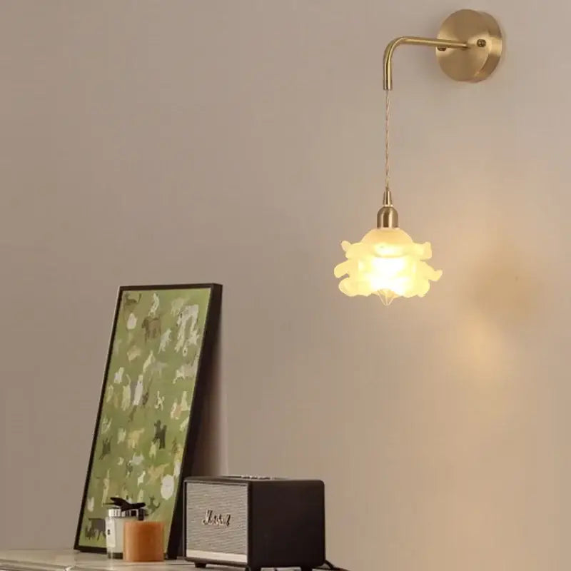 A warm-toned decorbites led glass wall lamp with petal design and brass mount for modern bedroom lighting