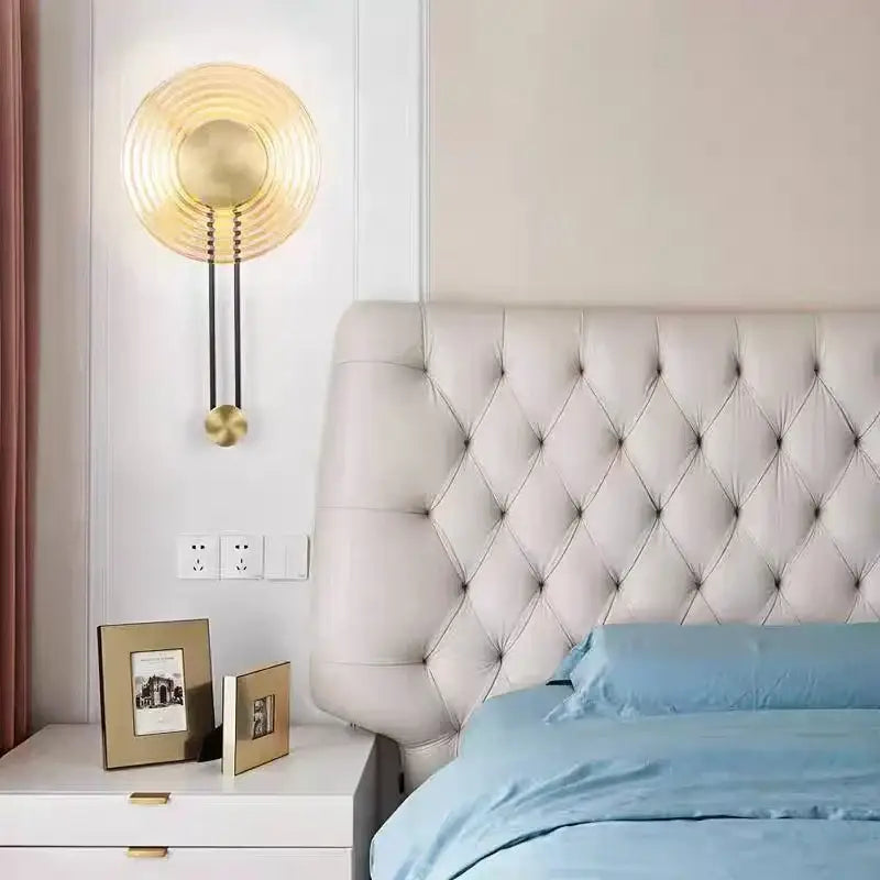 Gold-toned decorbites led glass wall lamp with concentric ridges and a dangling spherical accent for elegant lighting