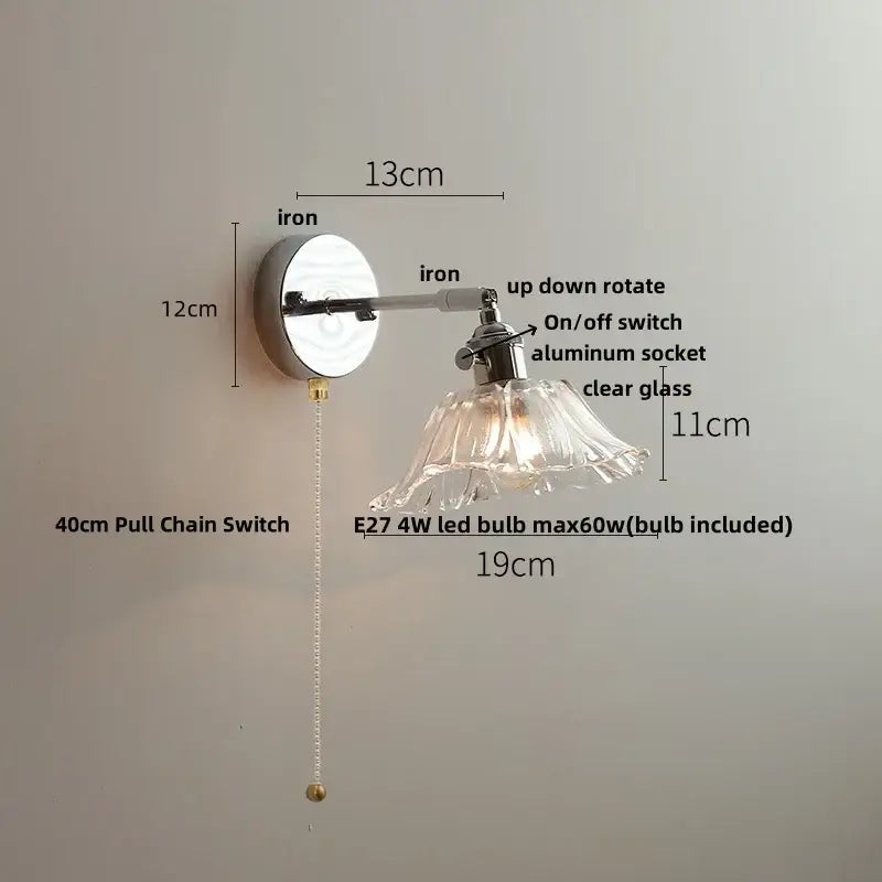 A sleek decorbites led glass wall light with polished iron base and clear flared glass shade for modern bedside use