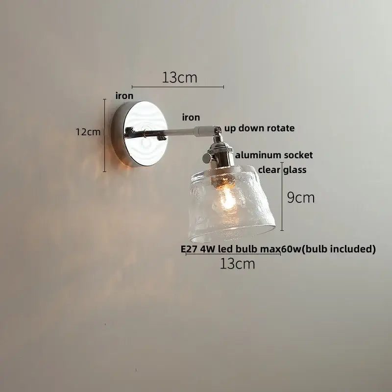 A sleek, adjustable wall light with polished iron base and clear textured glass shade by DecorBites LED Glass