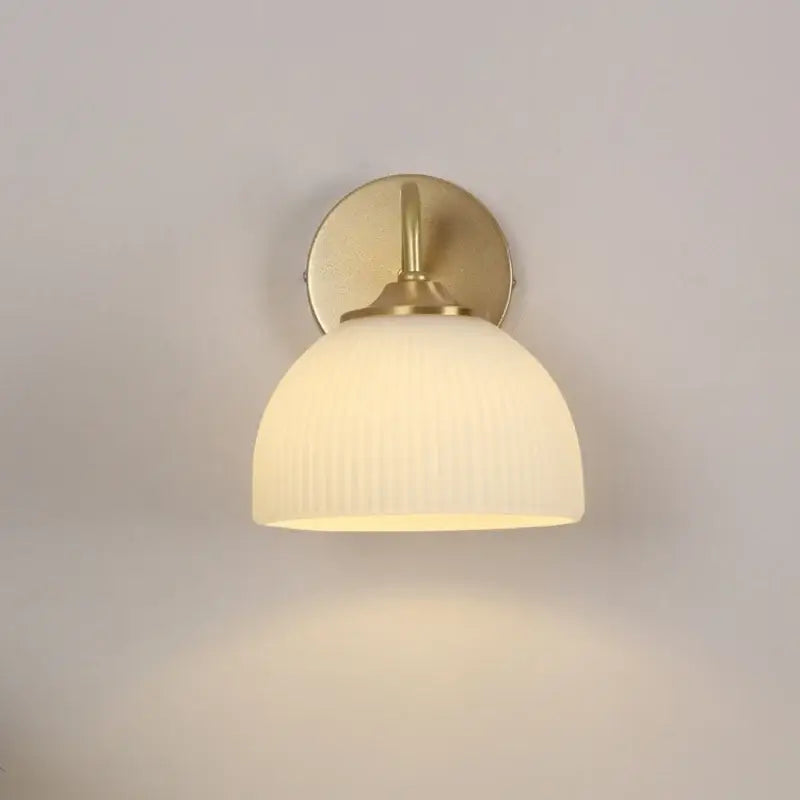 A warm-toned brass decorbites led glass wall sconce with ribbed off-white shade and pull chain switch