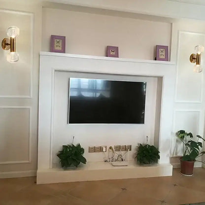 White fireplace surround with built-in tv mount and decorative shelf flanked by gold-toned decorbites™ glass wall sconces