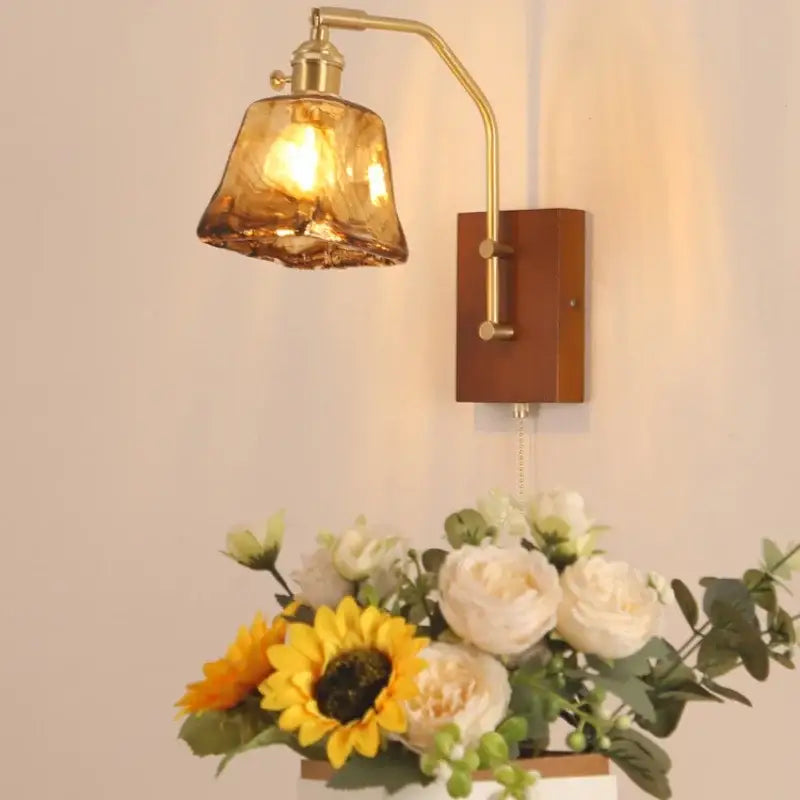 Brass-finished wall sconce with textured amber glass shade and wooden backplate for living room or bedroom use