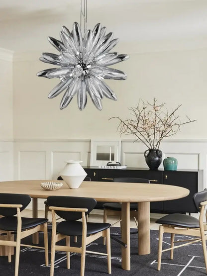 A modern silver-toned glass decorbites led globe chandelier with starburst design hangs above the dining table
