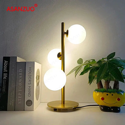 Gold-toned DecorBites™ LED table lamp with three vertical milk white glass lampshades on a slender stem