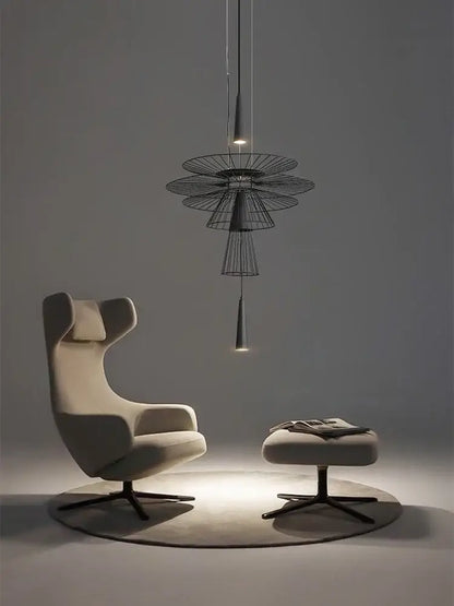 Cream-colored upholstered wingback armchair with black metal base shown with decorbites led iron pendant chandelier