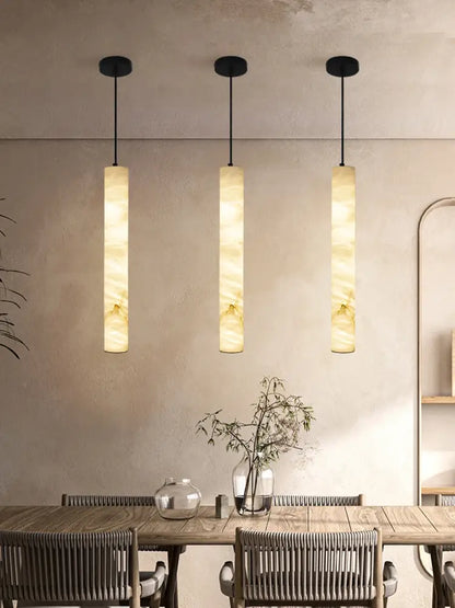 Three elegant led marble hanging lamps with warm beige and cream white alabaster shades hang from black fixtures