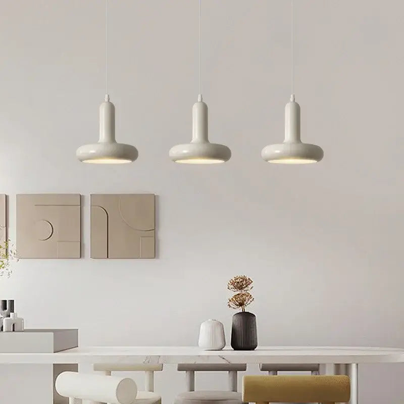 Three white decorbites led minimalist nordic pendant lights with cylindrical shades hang above a modern dining table