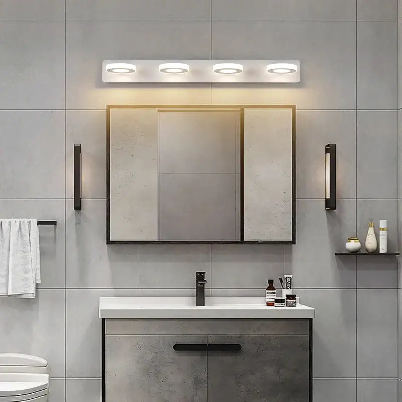 Modern white DecorBites led mirror light with four circular LED bulbs mounted above a mirrored medicine cabinet