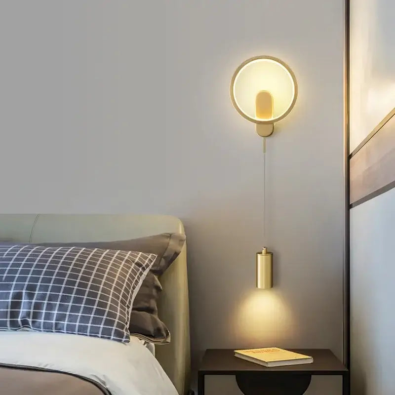 Gold-toned copper DecorBites™ LED moon wall light with cylindrical pendant emitting warm ambient illumination