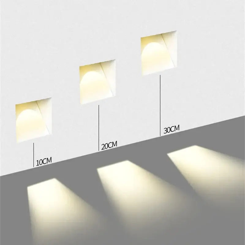 Three white DecorBites led motion sensor wall lamps with recessed square design and adjustable depths emitting warm glow
