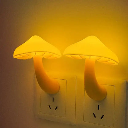 Two glowing yellow decorbites led mushroom night lights plugged into wall sockets with light controlled sensor for bedroom use