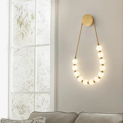Gold-toned DecorBites LED necklace wall lights with black metal base and white acrylic frosted globe bulbs in art deco style