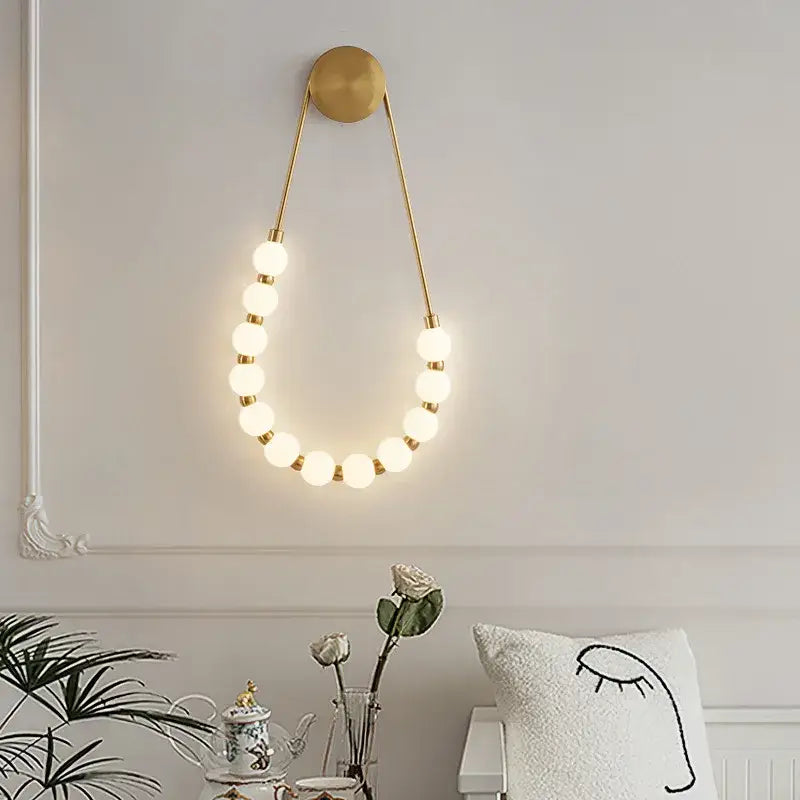 Gold-toned DecorBites LED Necklace wall lights with circular glowing bulbs in black metal and white acrylic sconce design