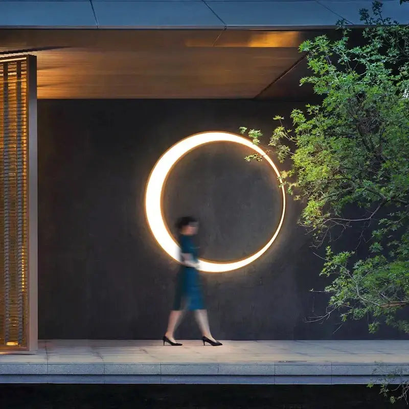 A decorbites led outdoor moon wall lamp emits warm golden light on a dark wall perfect for courtyard balcony use