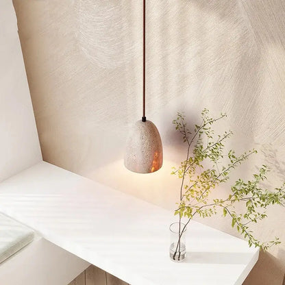 Minimalist decorbites led pendant lamp in yellow travertine with a warm glowing interior and textured concrete surface