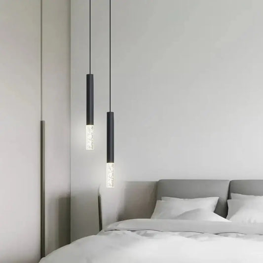 Two sleek black DecorBites LED pendant lights with frosted glass accents hang above a bed in a living room
