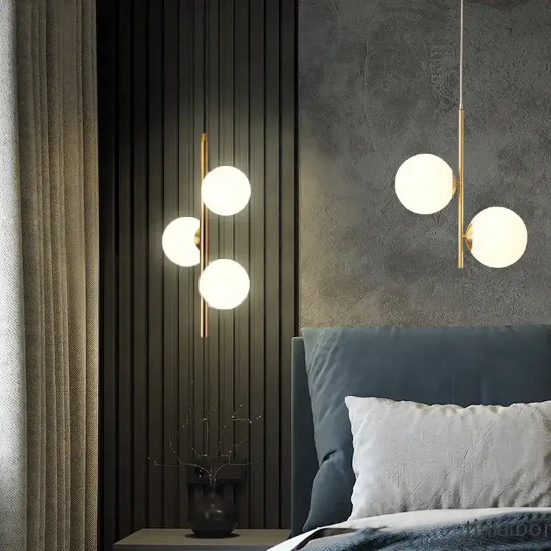 Modern gold-toned decorbites led pendant light with three glowing glass spheres hanging above a bed for home decor lighting