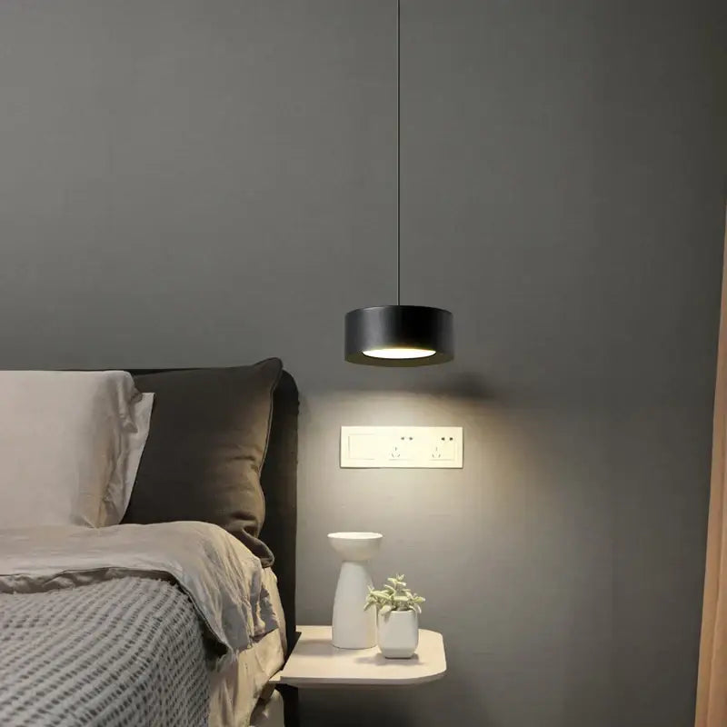 Black cylindrical decorbites led pendant light with modern design hanging above bedside table for bedroom decor