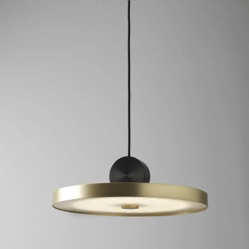 A modern decorbites led pendant light with a circular brass disc and matte black sphere for living room use