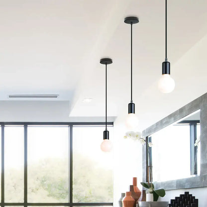 Three black decorbites led pendant lights with frosted glass bulbs hang as industrial ceiling fixtures