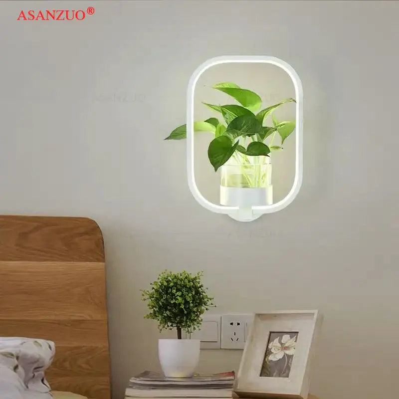 White oval wall lamps with integrated led illumination and clear glass container housing green plant for modern decor
