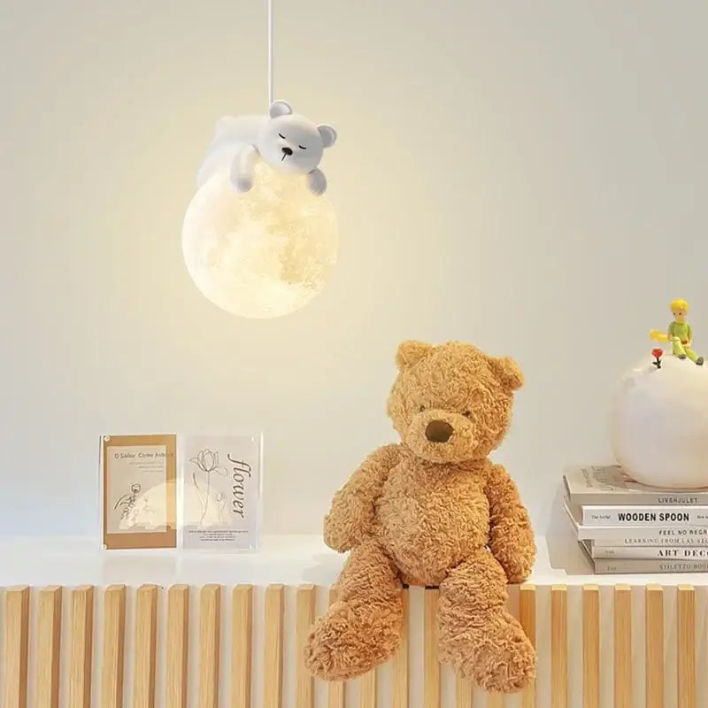 A soft plush tan teddy bear with a brown nose sits on a wooden shelf near a decorbites led rabbit pendant light