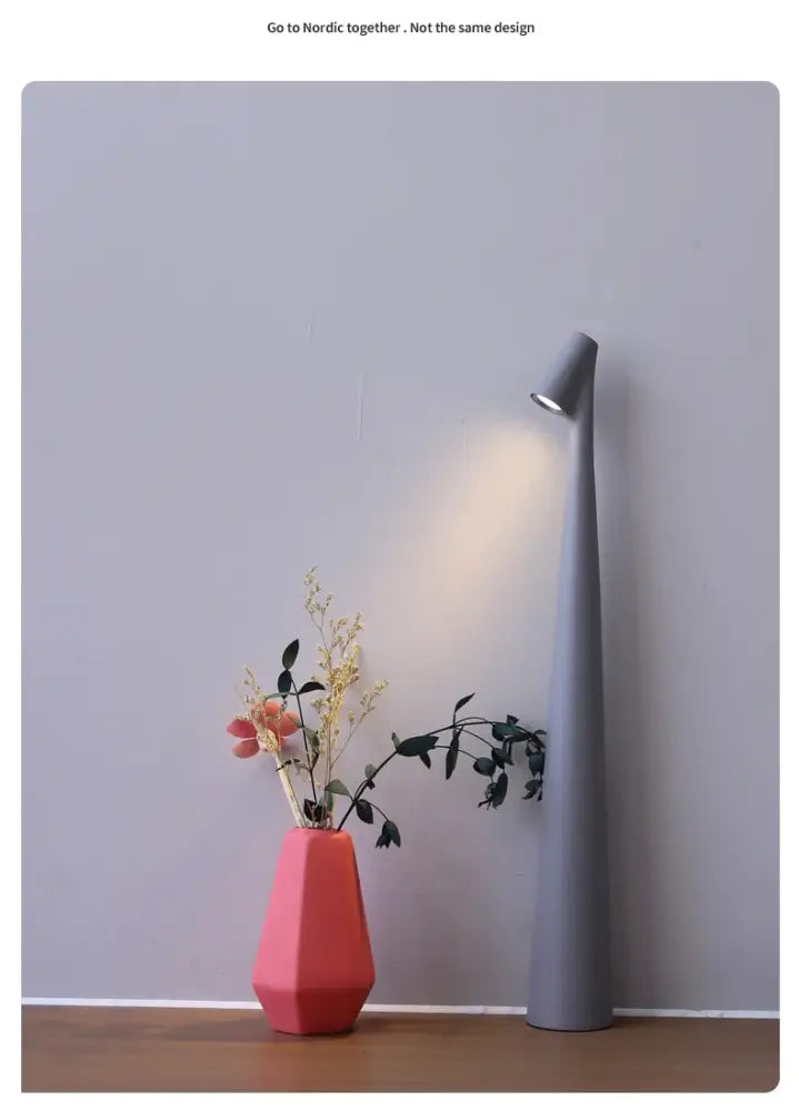 A coral-colored matte geometric vase next to a decorbites led rechargeable desk lamp for modern table lamp decor