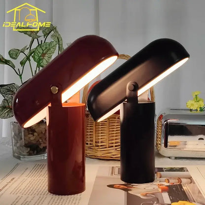 Two sleek decorbites led rechargeable table lamps with glossy burgundy and matte black finishes emitting warm light