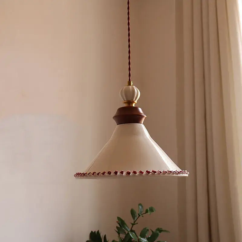 Cream-colored ceramic led rose flower pendant lamp with dark wood accent and red beaded trim by decorbites